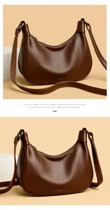 Detail van een bruine hobo tas van zacht leer met korrelstructuur en brede riem.