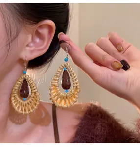 Detailed view of handmade ethnic rattan drop earrings with turquoise and wood beads
