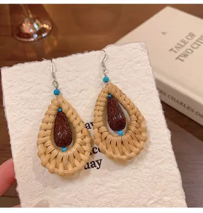 Detailed view of woven teardrop earrings with brown beads and ethnic style design