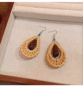 Close-up detail of handcrafted bohemian rattan teardrop earrings inside a jewelry display tray