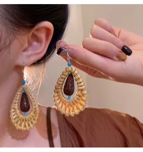 Detailed view of handmade ethnic rattan woven water drop earrings with blue bead accents.