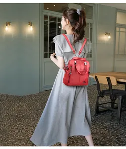 Donna elegante che indossa un grande zaino in pelle rossa in un caffè dal design moderno