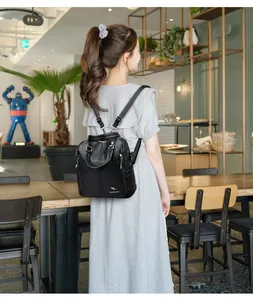 Grande zaino in pelle nera da donna presentato in un ambiente casual da caffè.