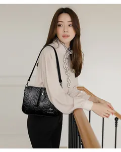 Detailed view of a black embossed rose handbag worn by a model in a stylish indoor setting.