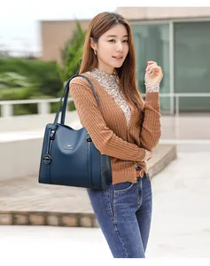 Elegant woman carrying a blue large capacity leather commuter shoulder bag outdoors.