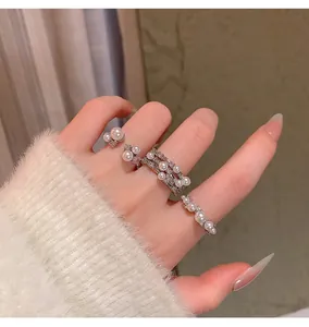 Close-up of elegant French style pearl rings stacked on finger with fuzzy sweater