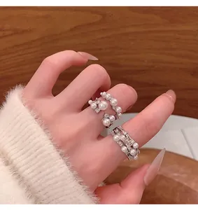 Detailed view of elegant French-style pearl rings with shimmering crystals on hand.