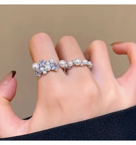 Detail view of French style adjustable pearl and crystal stackable rings on fingers.
