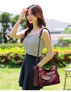 Burgundy leather bag with multiple zip pockets shown in a natural outdoor setting