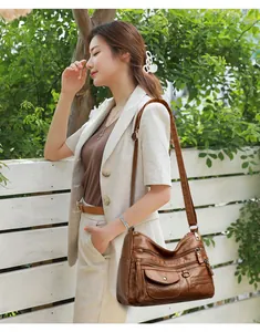 Elegant brown synthetic leather multi-zip crossbody bag worn by model in a garden