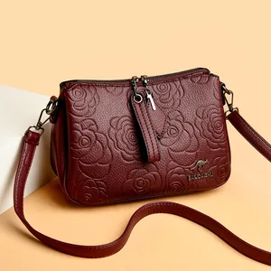 Elegant wine red leather crossbody bag featuring embossed rose patterns and a metal kangaroo logo