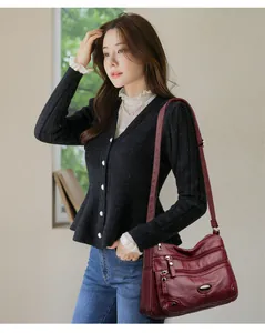 Burgundy multi-pocket soft leather shoulder bag for women worn by a model in a casual setting