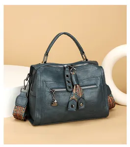 Detailed view of teal textured leather Boston bag with patterned strap and silk scarf