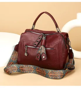 Detail showing a burgundy Boston bag with a vibrant geometric patterned wide strap.