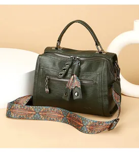 Detailed view of fashionable dark green Boston handbag featuring a colorful ethnic strap