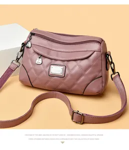 Dettaglio di una borsa a tracolla trapuntata in morbida pelle malva con diverse cerniere