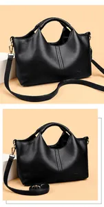 Close-up of black textured leather handbag with gold hardware and strap details.