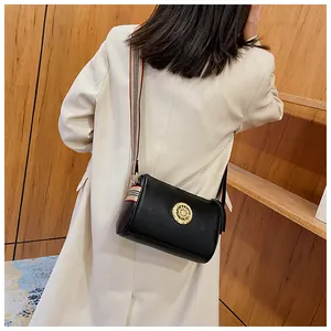 Vista dettagliata di una borsa a tracolla retrò in pelle nera con tracolla a righe su modella