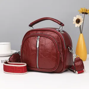 Modische burgunderrote Handtasche mit mehreren Fächern und breitem gewebtem Gurt.