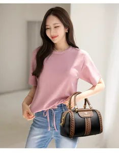 Stylish color-block women's handbag held by a model in a casual pink outfit.