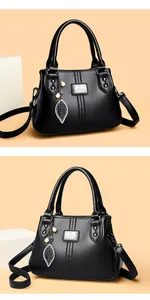 Detailed view of black textured faux leather handbag with leaf and pearl pendant