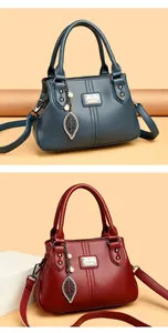 Close-up view of two elegant leather handbags in teal and red featuring leaf charms