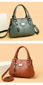 Detailed view of elegant women's leather handbags in green and brown with leaf charms