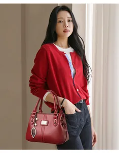 Close-up view of an elegant wine red faux leather handbag with leaf charm accessory