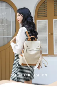 Side view of a stylish cream and brown anti-theft women's backpack on an Asian model.