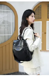 Detail view of a black oil wax leather backpack worn by a model in a cafe setting