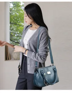 Lifestyle detail of a textured blue leather handbag worn by a model
