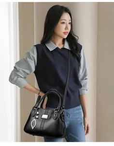 Black leather handbag with leaf charm shown on a model for everyday elegant style
