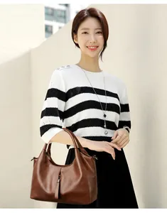 Asian model holding a fashionable brown soft leather handbag with minimalist casual design