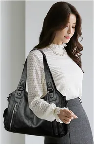 Close-up of elegant model carrying a large black retro soft leather shoulder tote bag