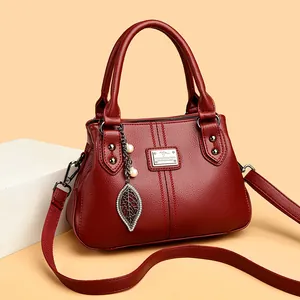 Elegant red leather handbag for women with leaf charm and shoulder strap