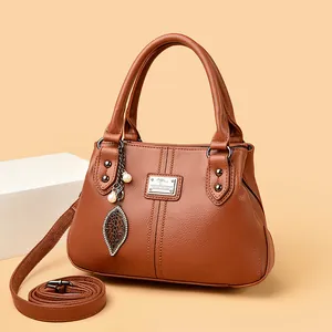 Elegant brown leather handbag for middle-aged women with leaf pendant and strap