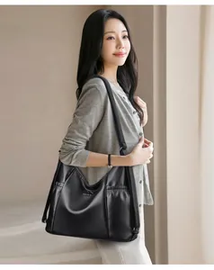Asiatisches Model präsentiert eine große schwarze Leder-Umhängetasche für den Alltag