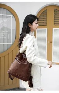 Fashionable woman carrying a brown vintage leather anti-theft backpack outdoors