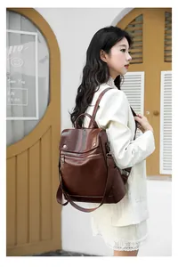 Stylish brown leather backpack presented on a model in a casual outdoor setting