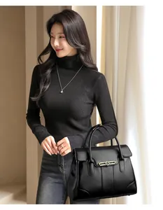 Close-up of elegant black leather handbag with gold buckle held by model