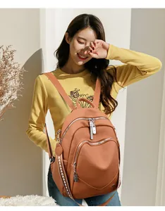 Elegante zaino in morbida pelle color terracotta indossato da una modella asiatica in un set luminoso
