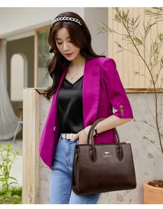 Bolso tote de cuero marrón oscuro llevado por modelo con un look profesional elegante