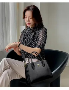 Elegante bolso tote negro de moda con logotipo de canguro, llevado por una modelo.