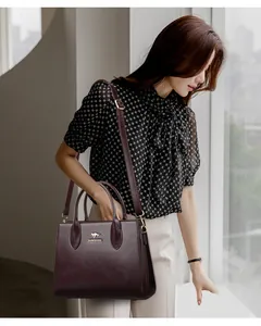 Vista detallada de un elegante bolso tote de cuero burdeos llevado por una modelo de moda