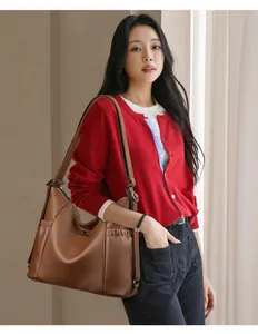 Elegante braune Leder-Schultertasche, präsentiert von einem asiatischen Model in Rot