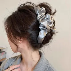 Detailed side view of a large silver fabric scrunchie hair claw clip worn in hair