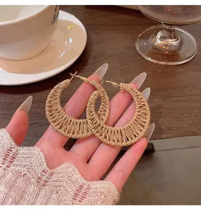 Close-up of handmade natural straw woven crescent hoop earrings for a bohemian vacation look