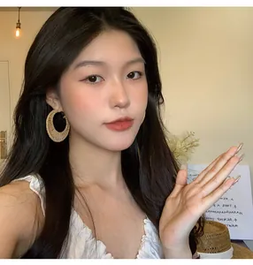 Close-up of model wearing handmade straw rattan hoop earrings in vacation style