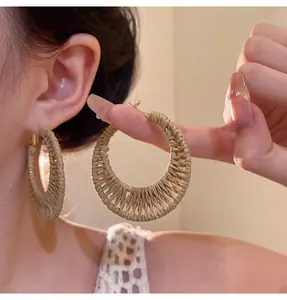 Close-up of handmade straw woven hoop earrings with bohemian vacation style for women.