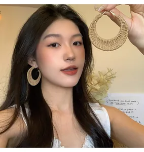 Detailed view of handmade straw woven hoop earrings for beach style and summer outfits